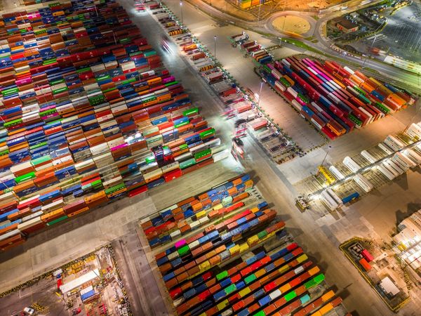 Aerial view of a large container port showing hundreds of standardized shipping containers in uniform rows